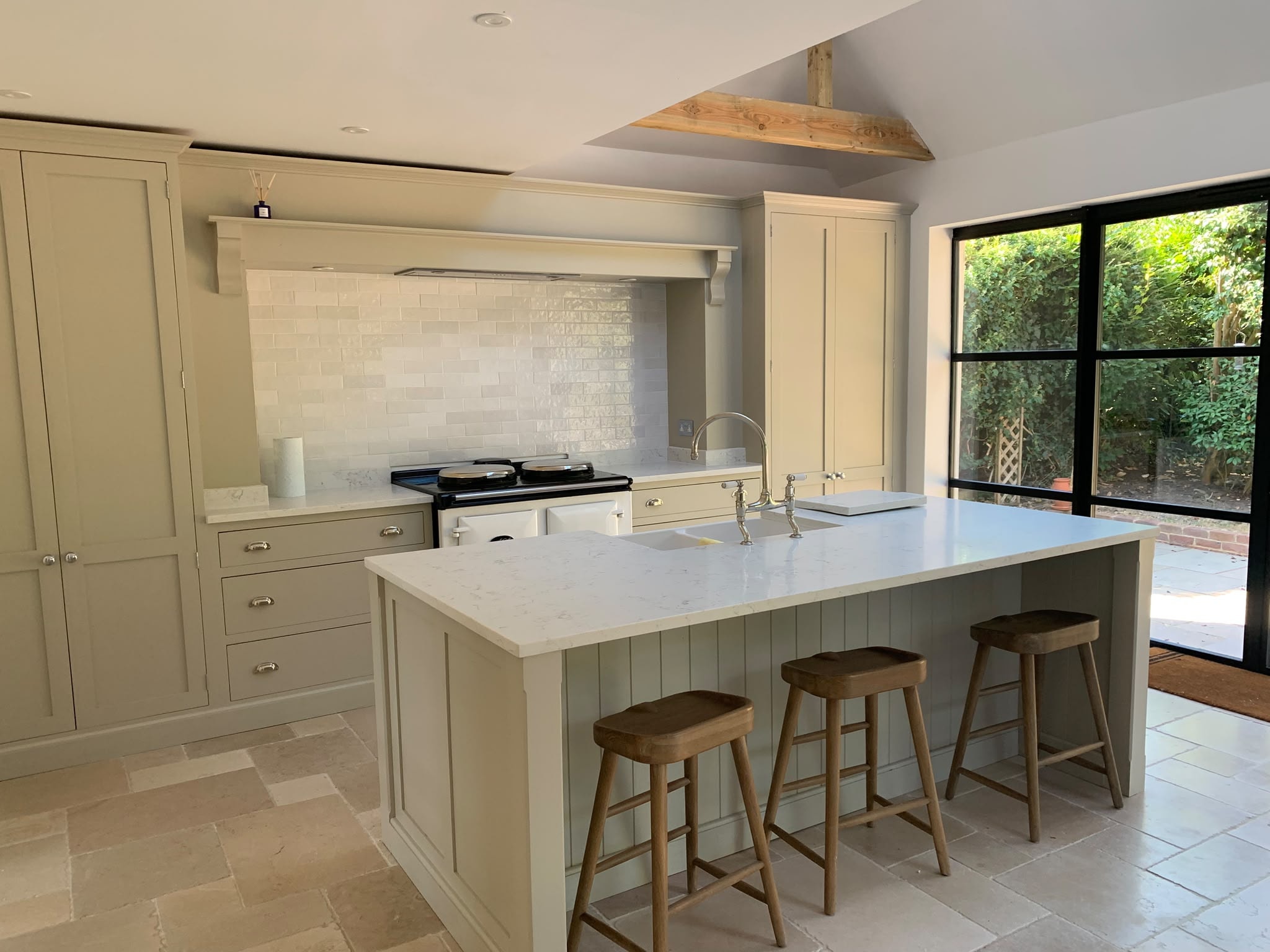 Sage green shaker kitchen with Aga and marble island after new build clean