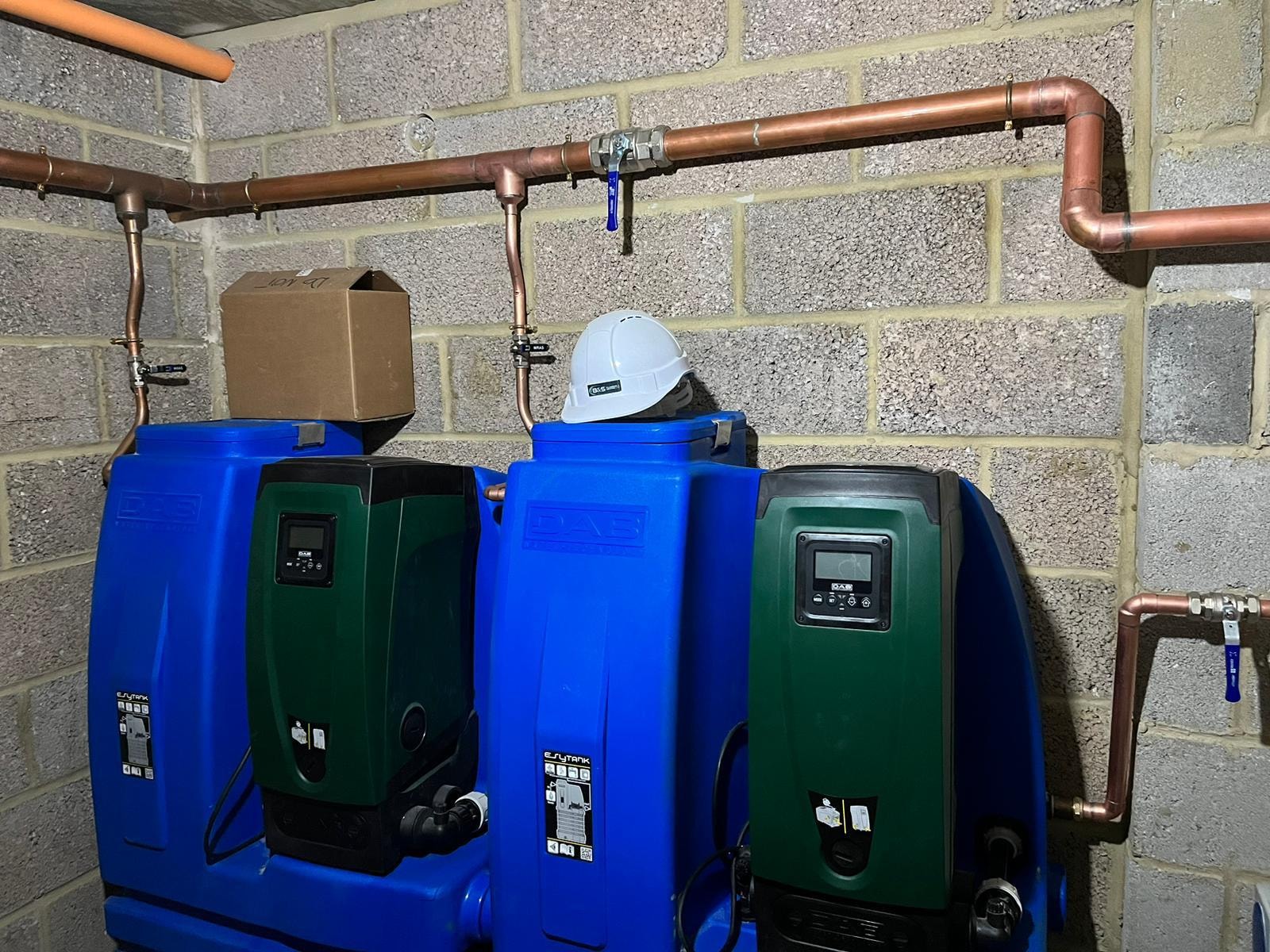 Underfloor heating pump units and copper pipework installed in plant room — Surrey